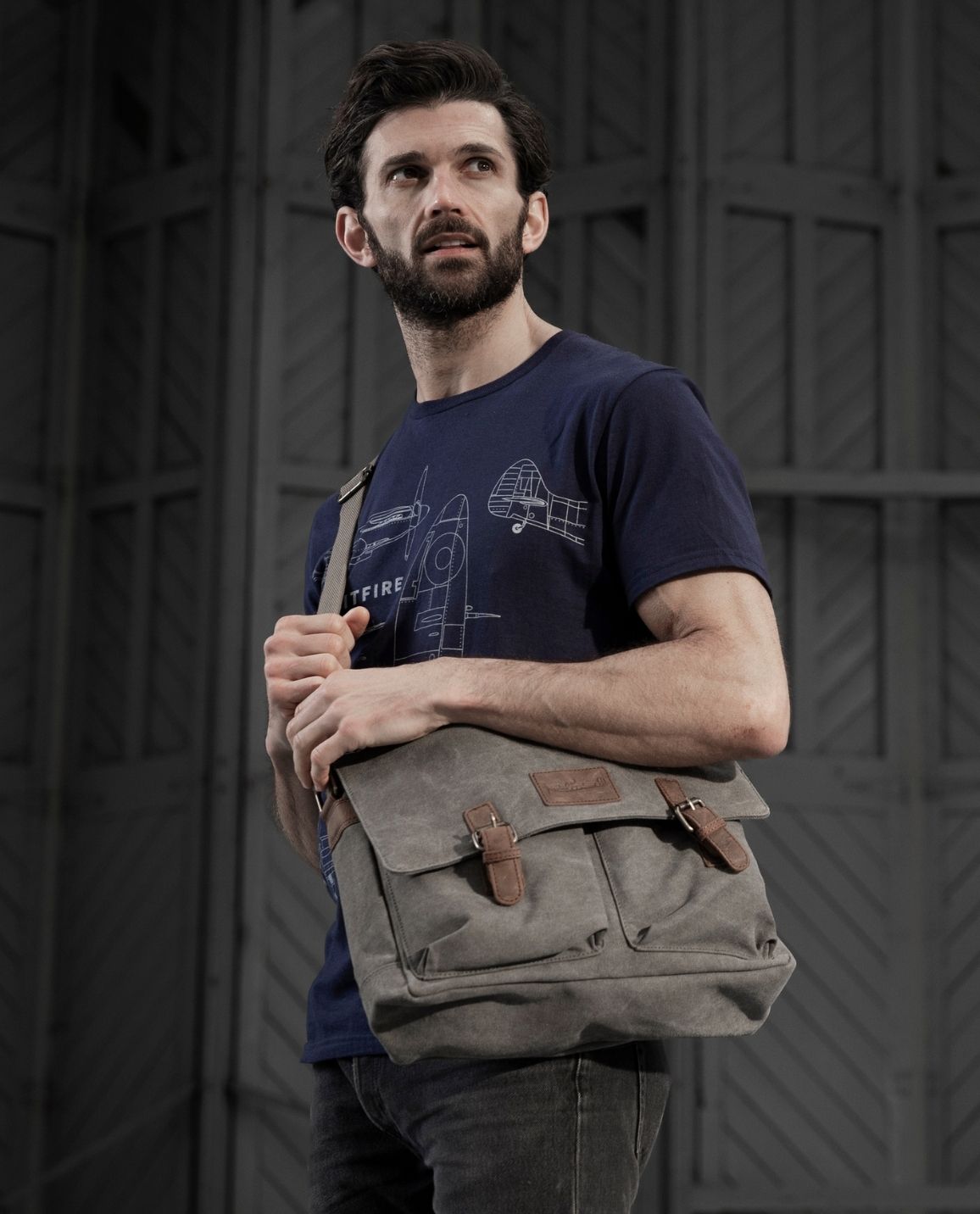 Man wearing blue spitfire blueprint T-Shirt holding Spitfire Canvas Messenger Bag.