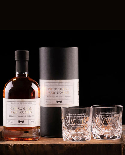 Bottle and packaging of Churchills War Room whisky with two glasses on a wooden surface.